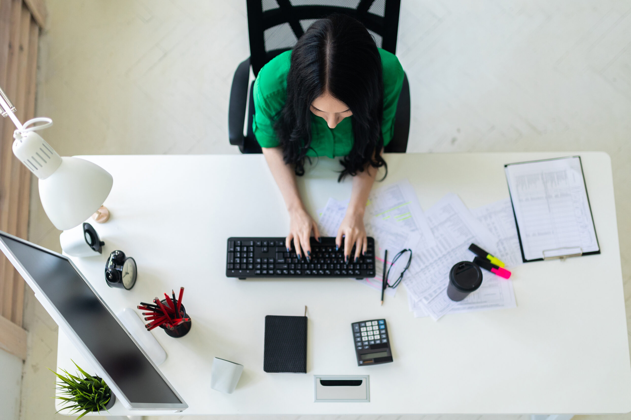 Top view of a young girl sitting at an office desk and typing on a keyboard