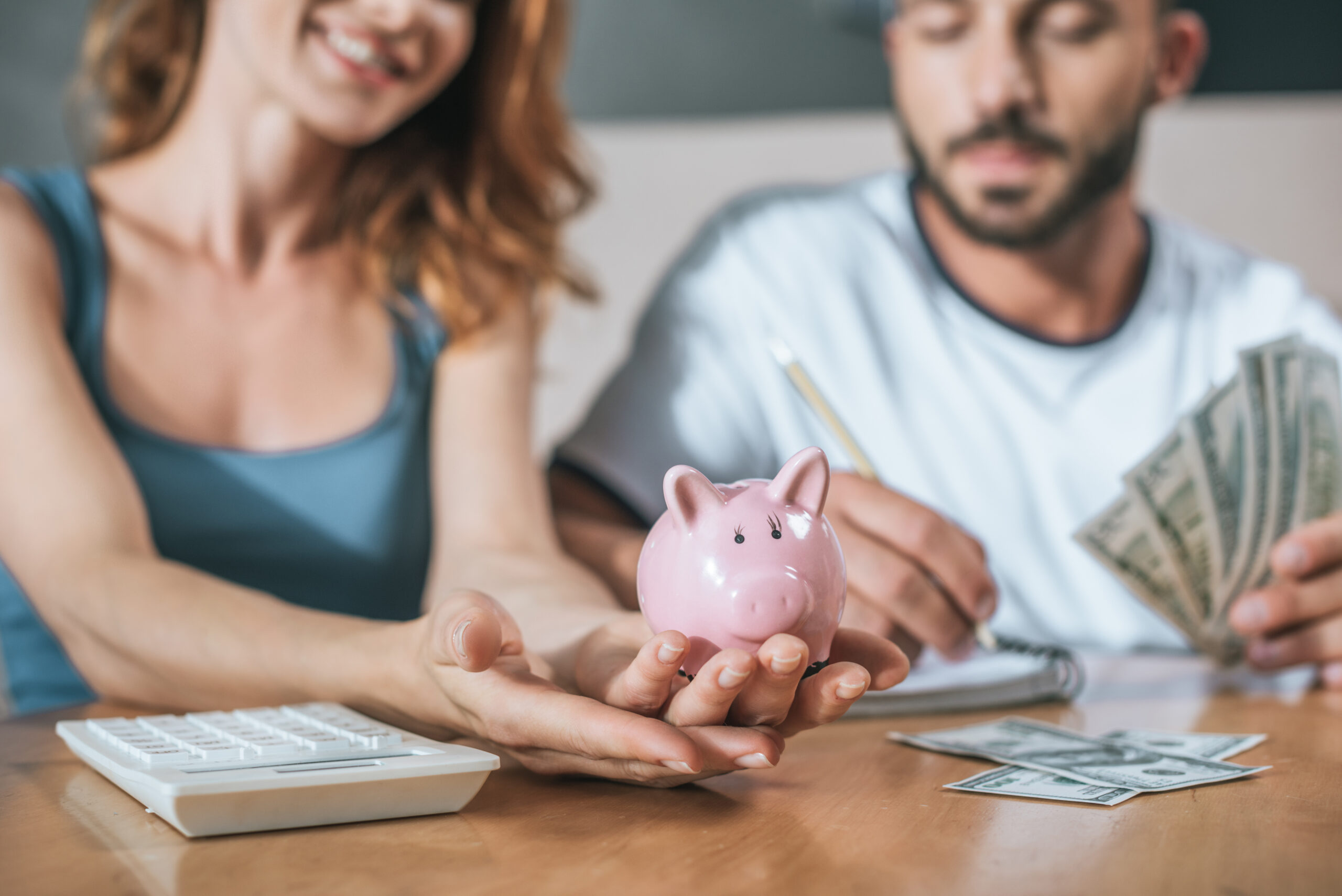 couple holding a piggy bank, reviewing finances