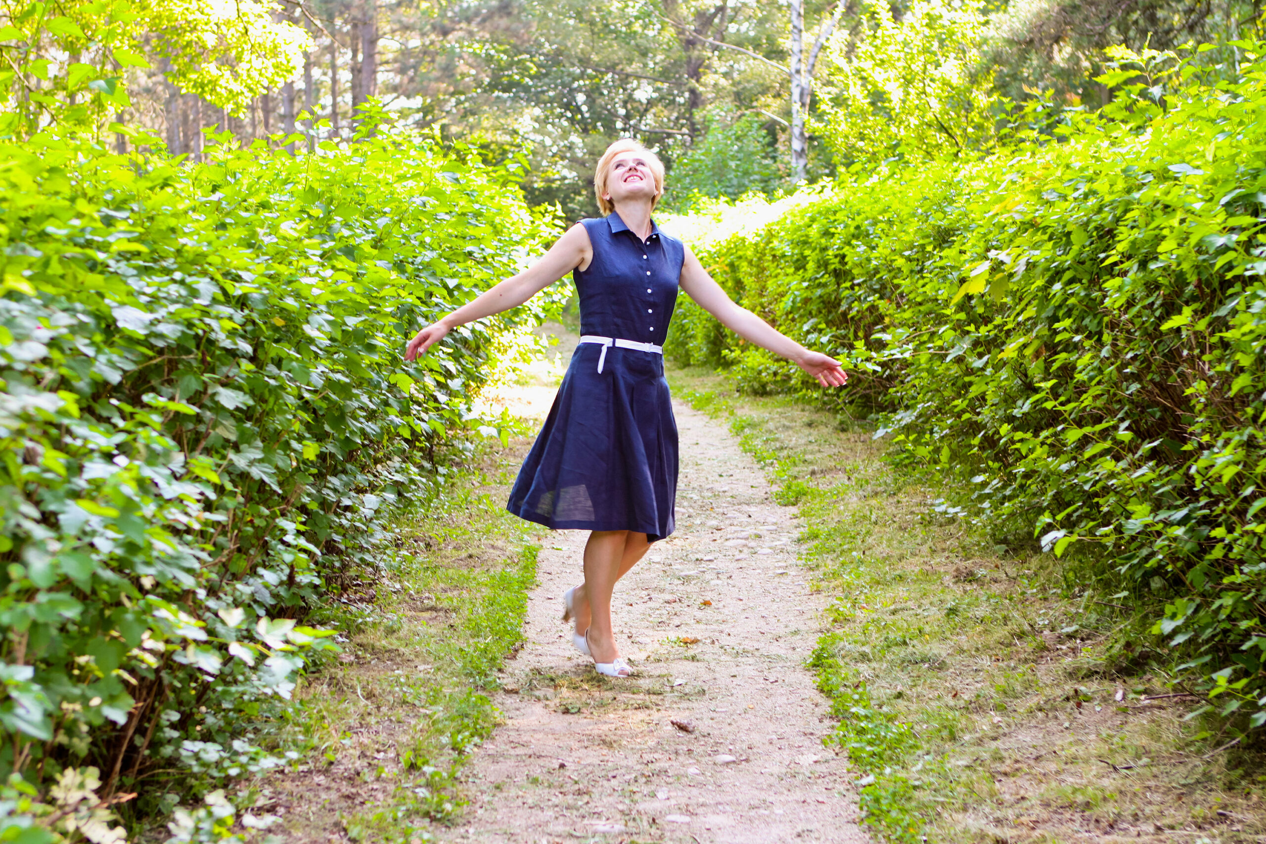 Woman spinning happily in a beautiful garden path