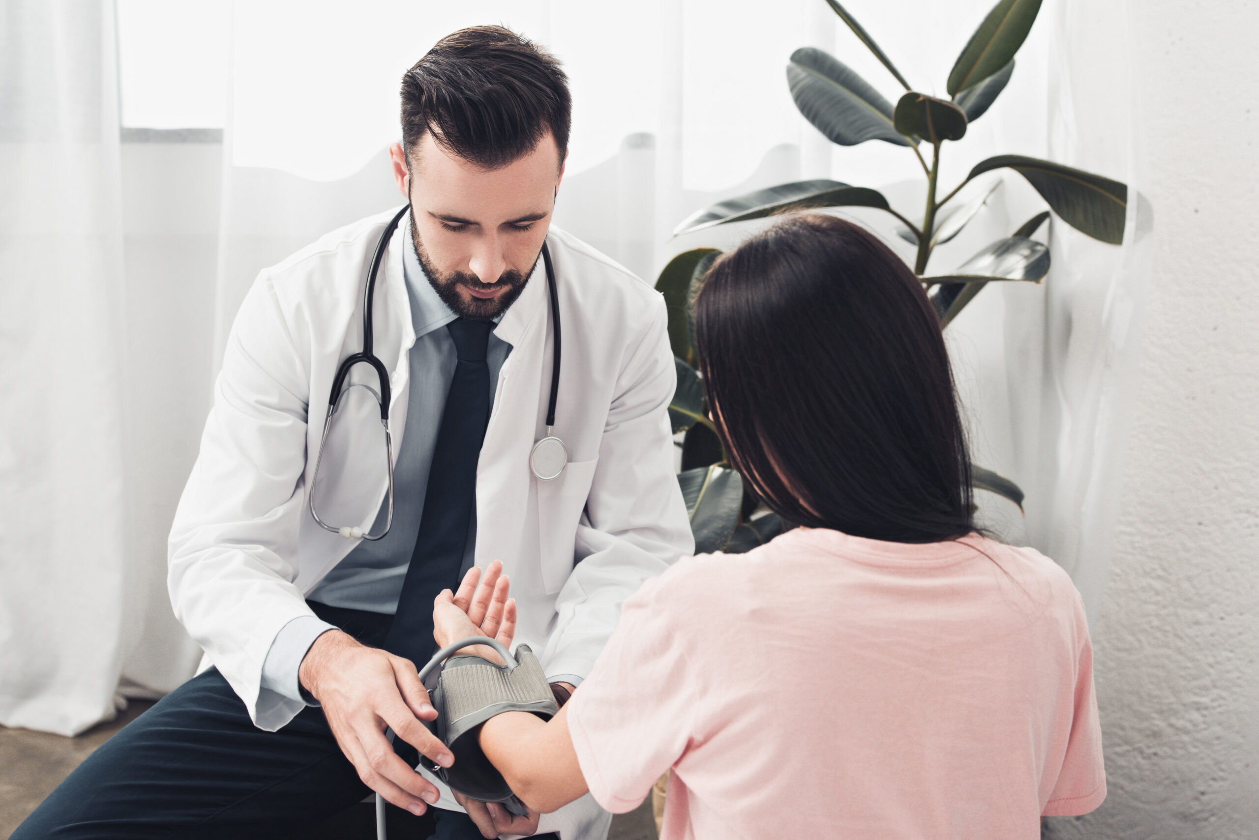 handsome young doctor measuring blood pressure of patient