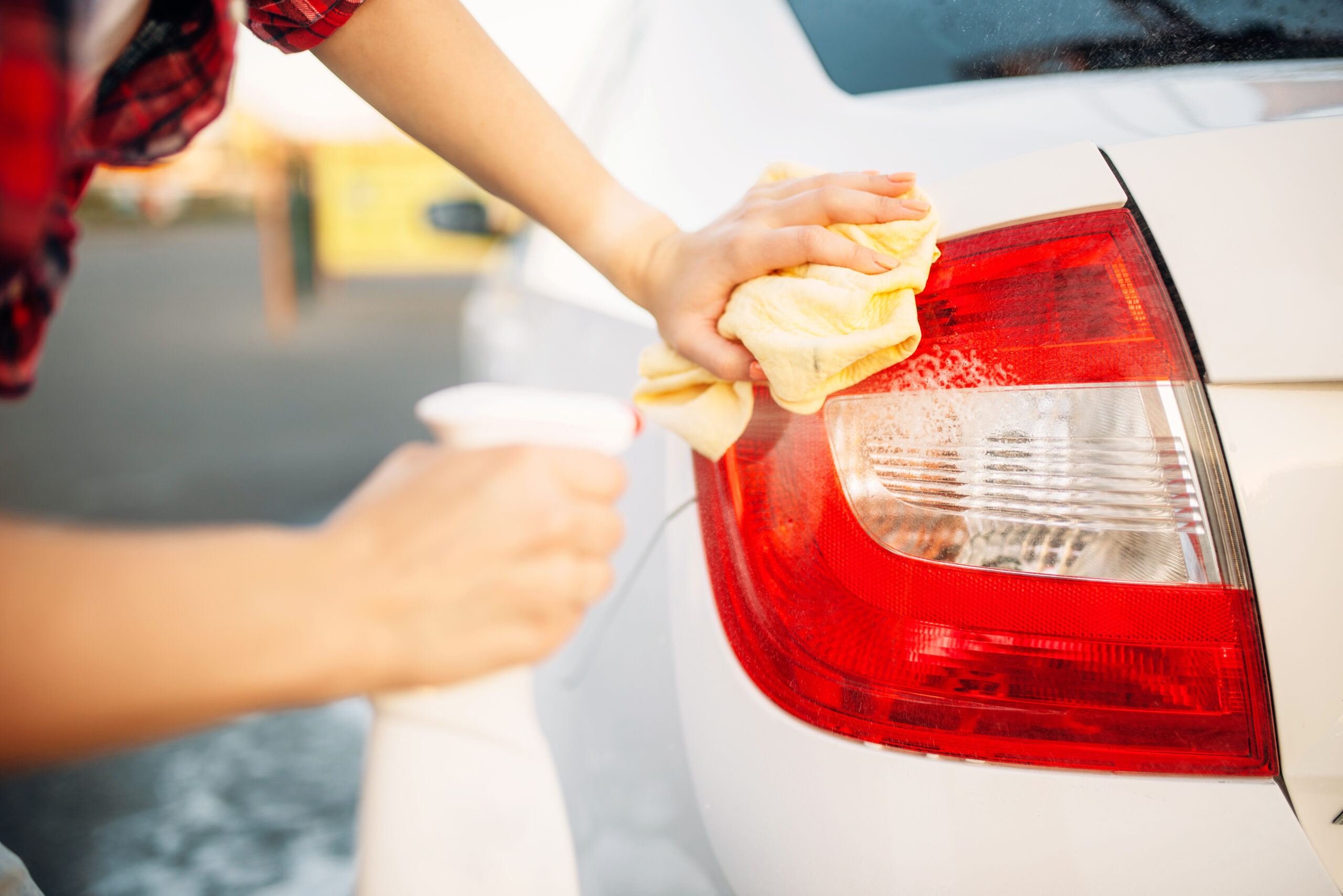 Woman cleans rear lights of the car with spray