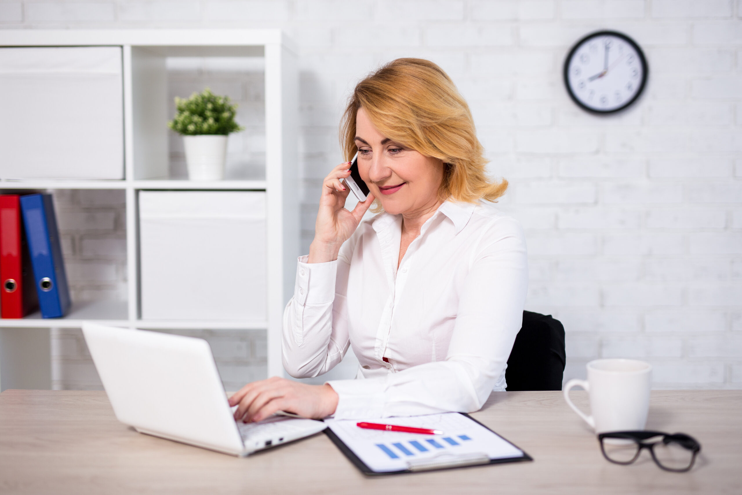 cheerful mature business woman sitting in office and talking by