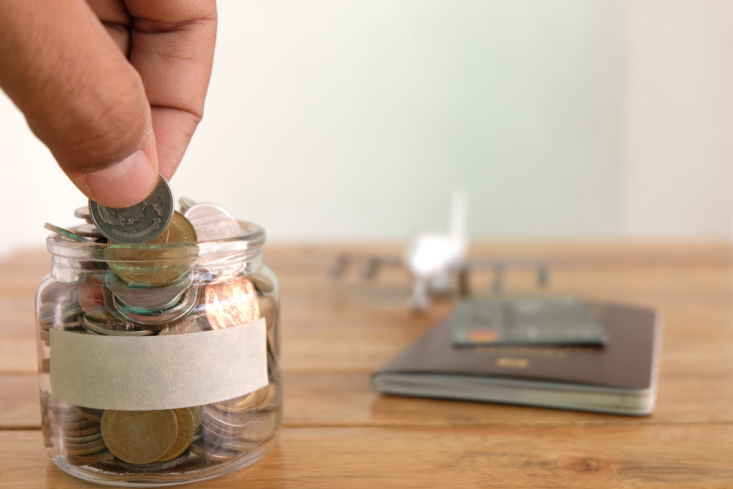 Hand putting coin in glass savings jar