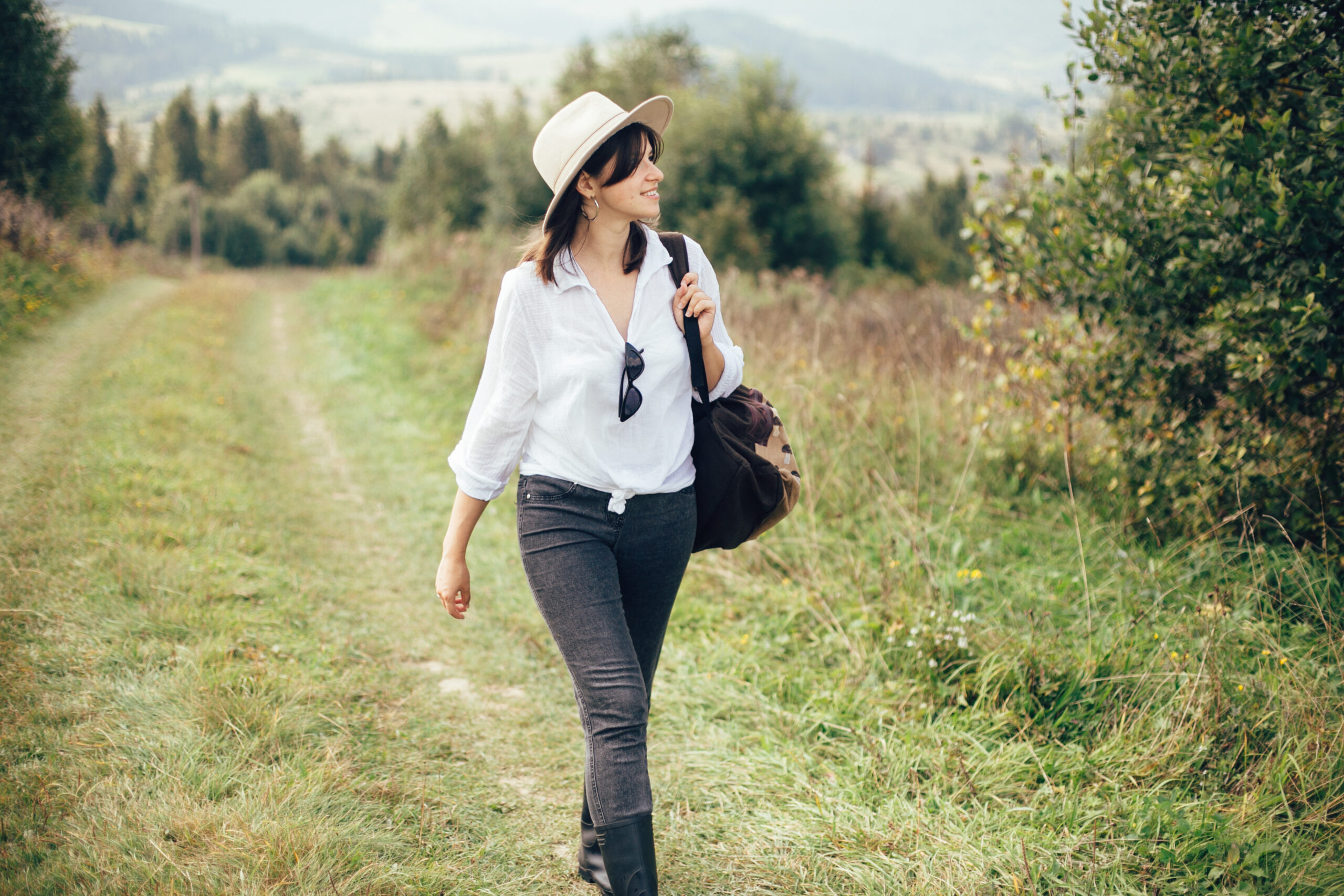 Happy hipster girl with backpack traveling on top of sunny mount