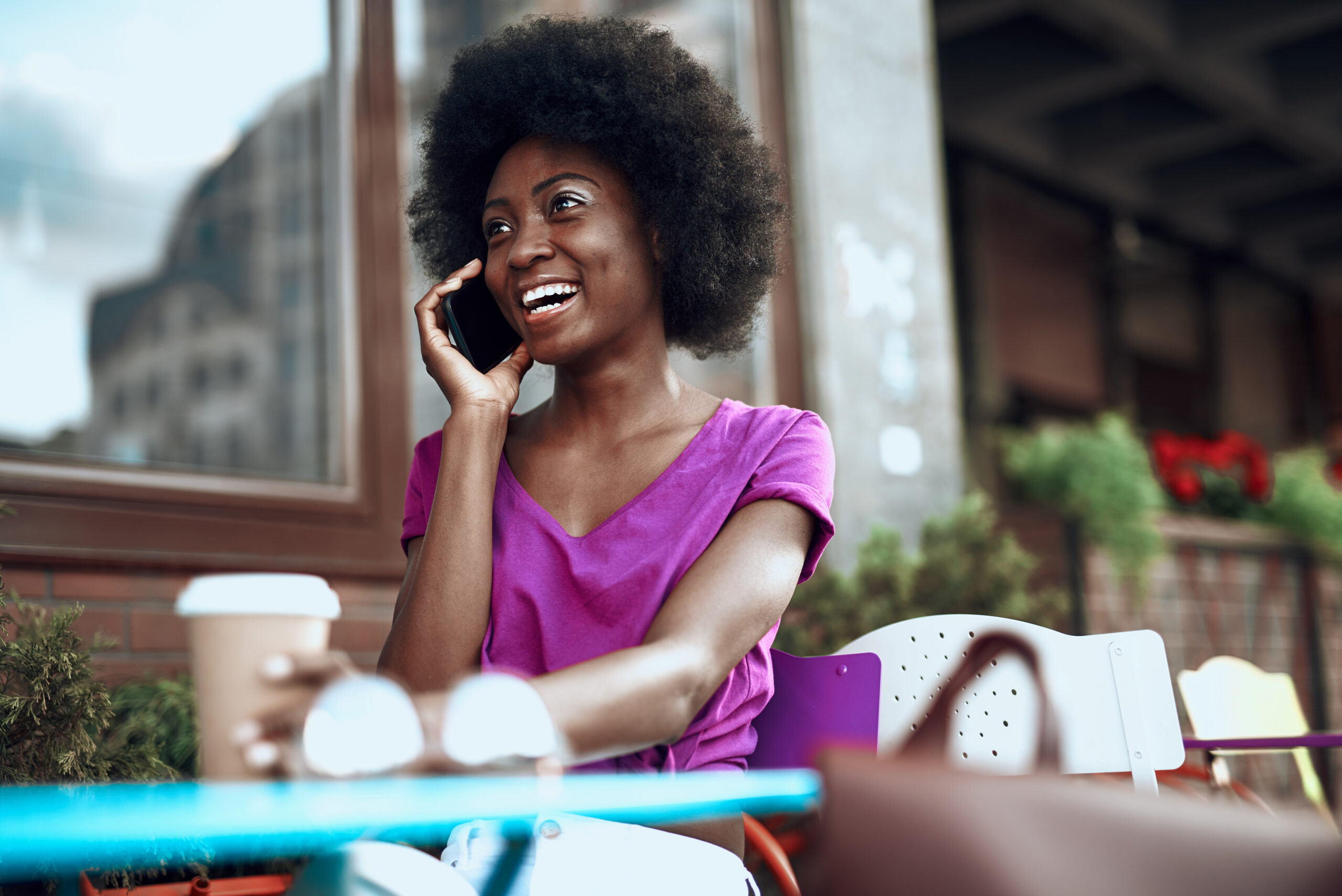 Beautiful happy woman speaking by smartphone in cafe