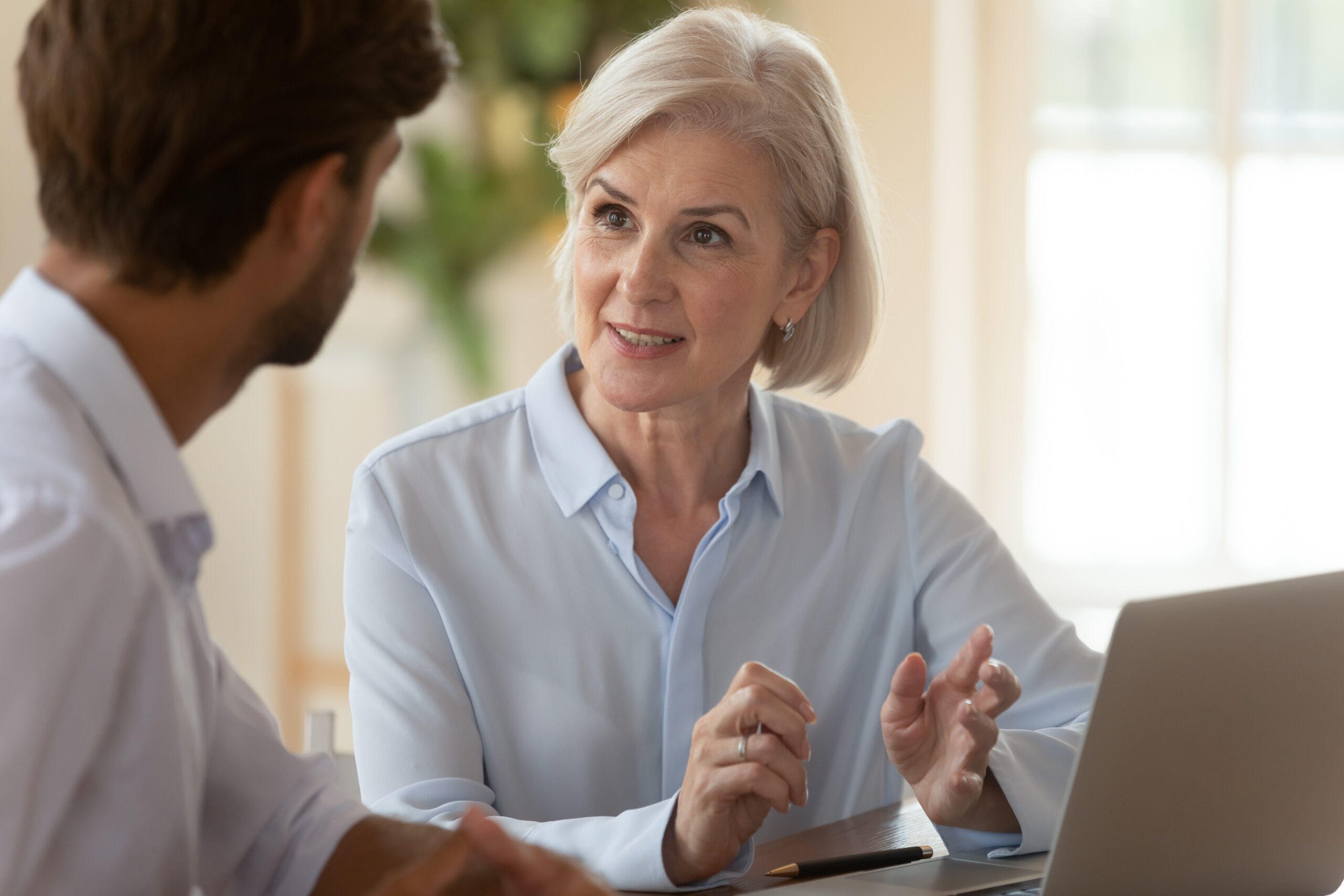 Middle aged businesswoman manager speaking to businessman client teaching intern