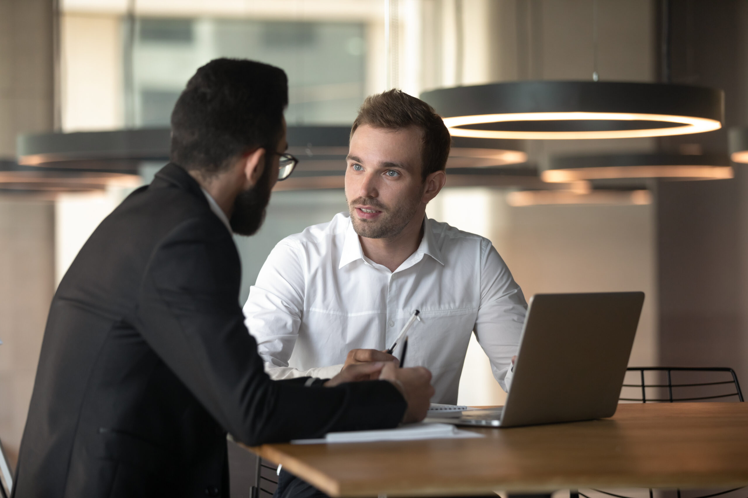 Young businessmen cooperating using laptop in office