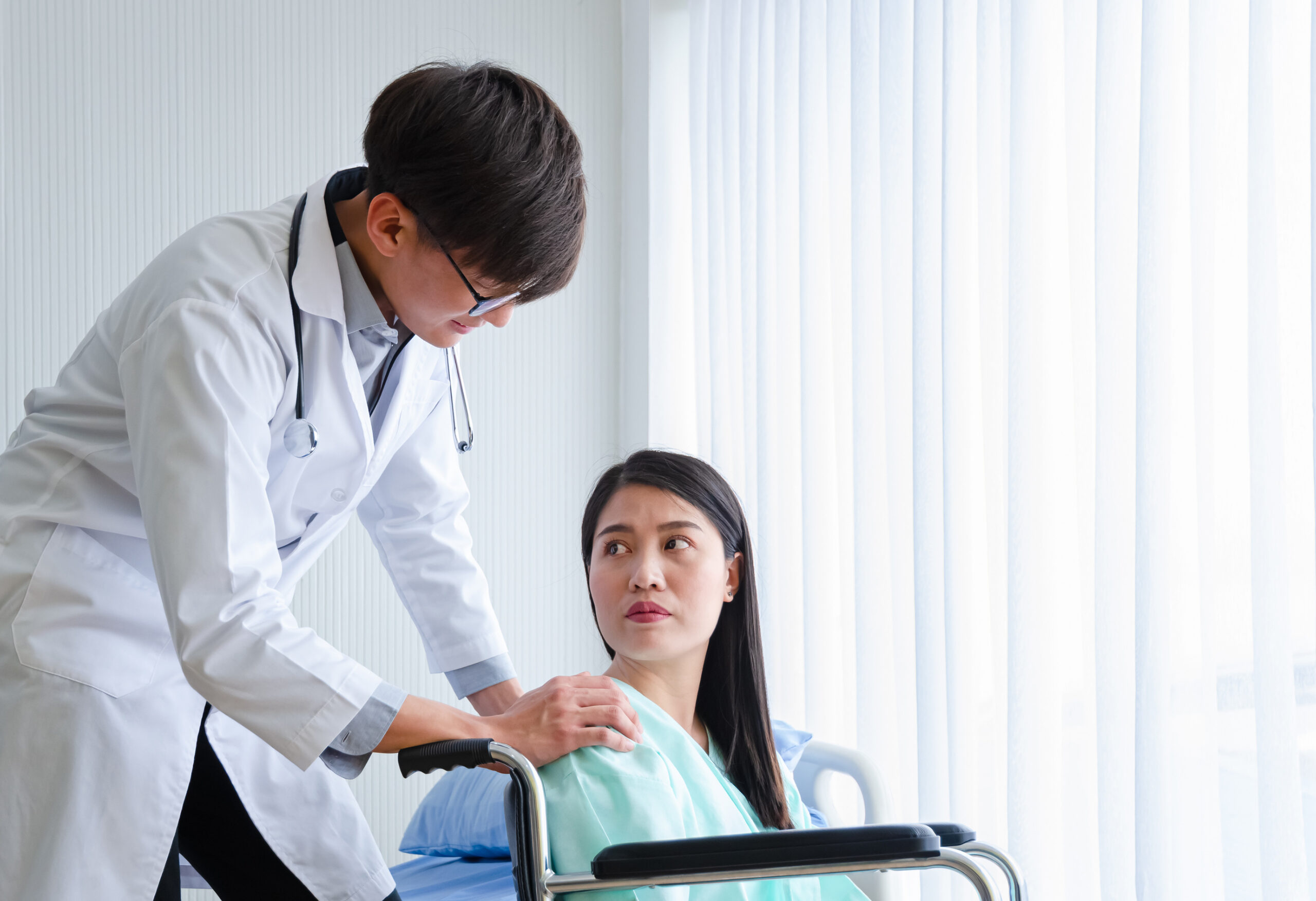 Asian male physician doctor encourage disabled female patient s