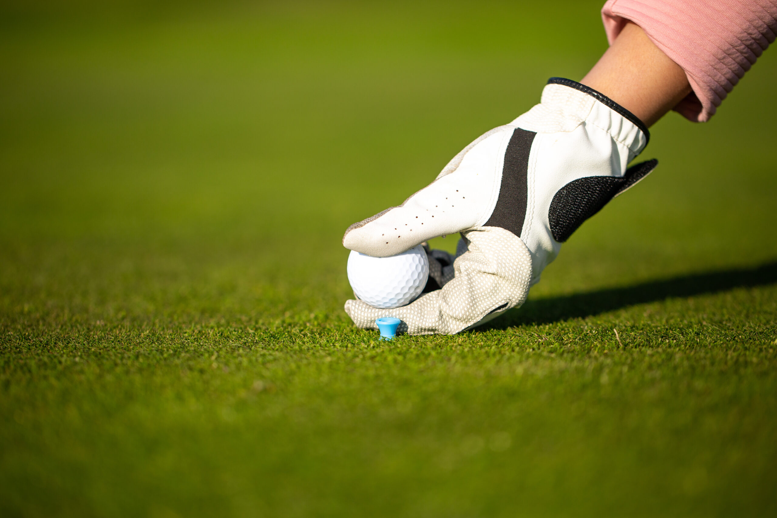 Golf player placing ball on tee