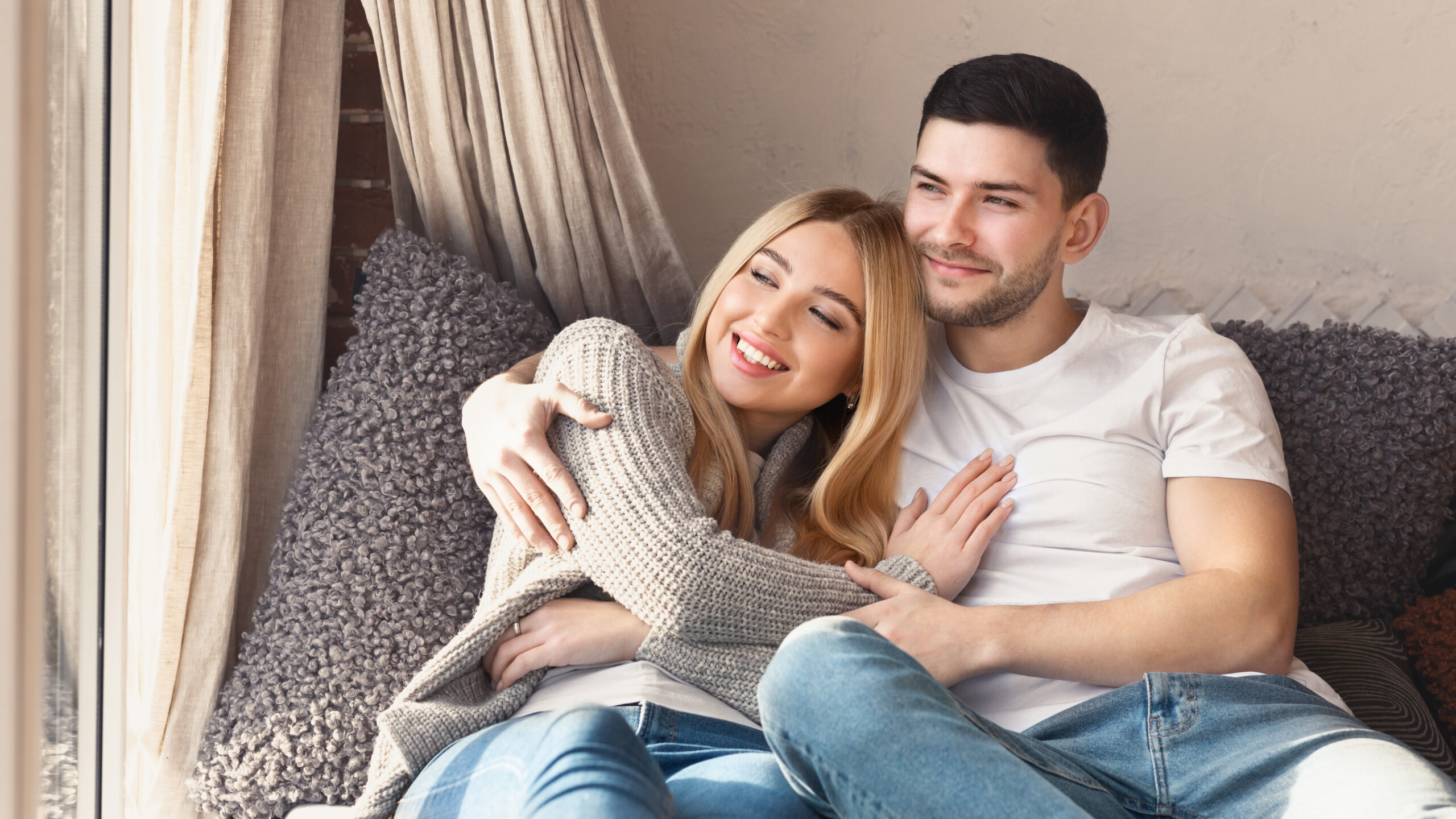 Lovely young couple cuddling on sofa at home