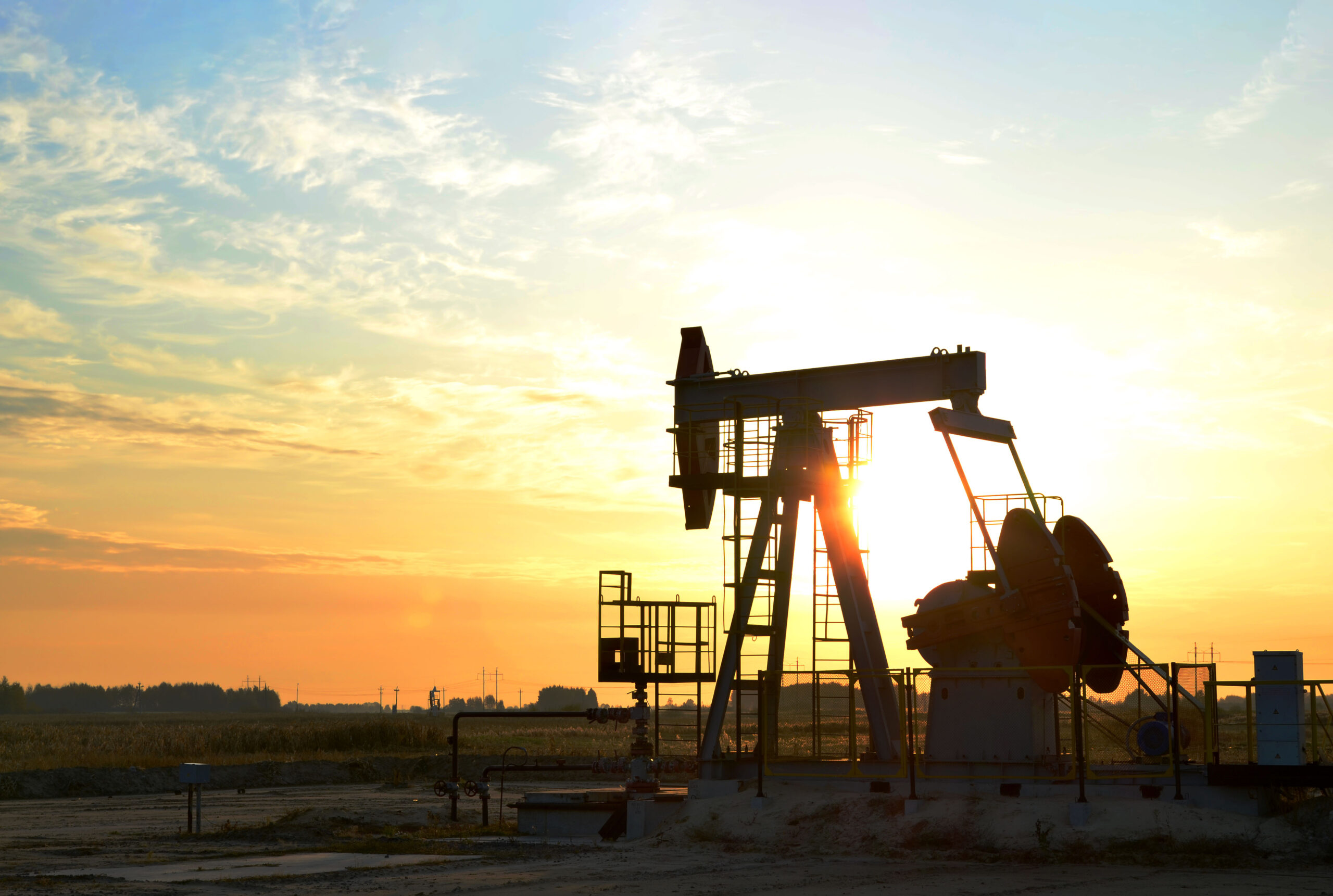 Oil drilling dericks at desert oilfield for fossil fuels output and crude oil production from the ground. Oil drill rig and pump jack.