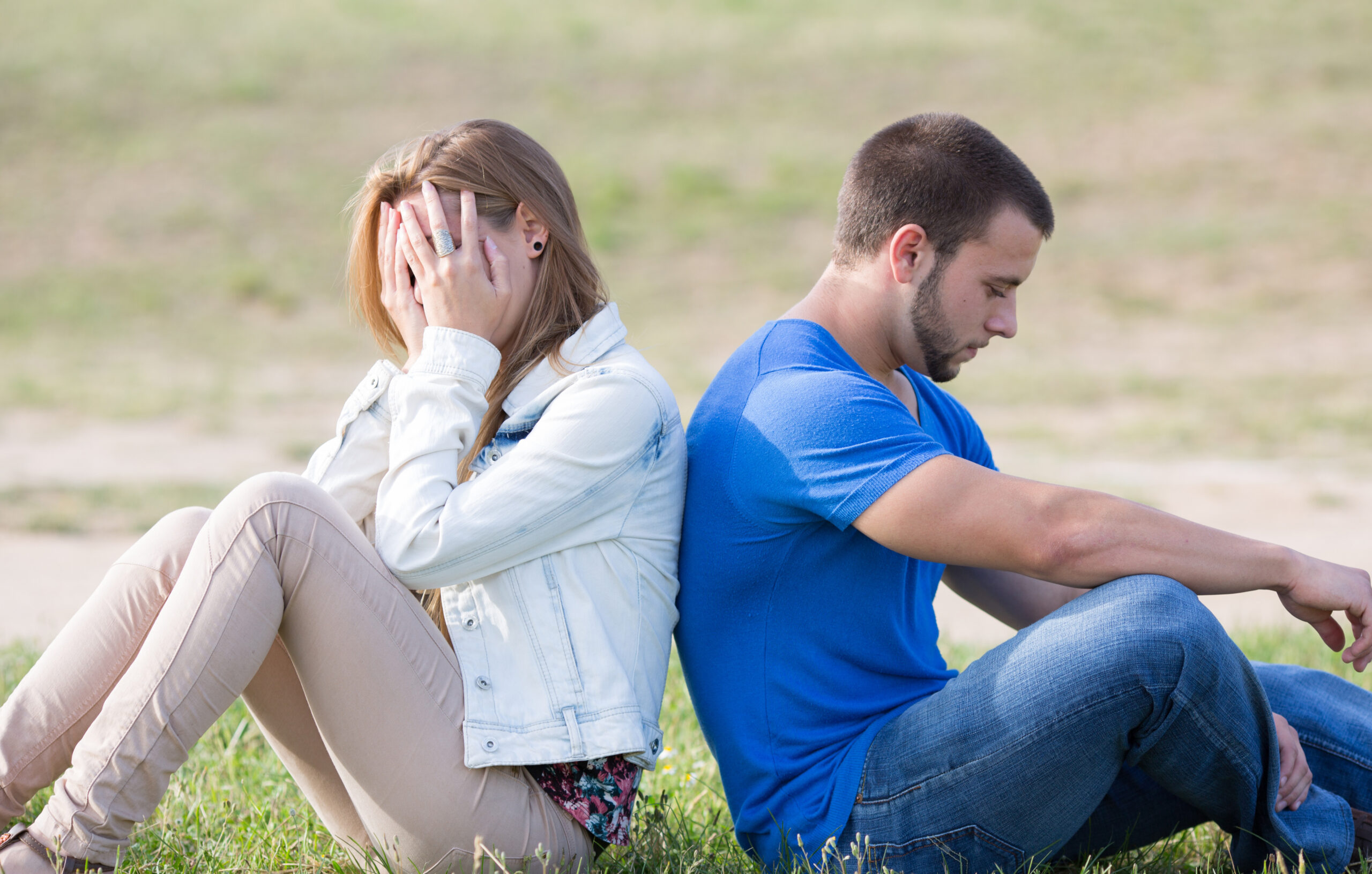 Fighting couple sitting back to back outside