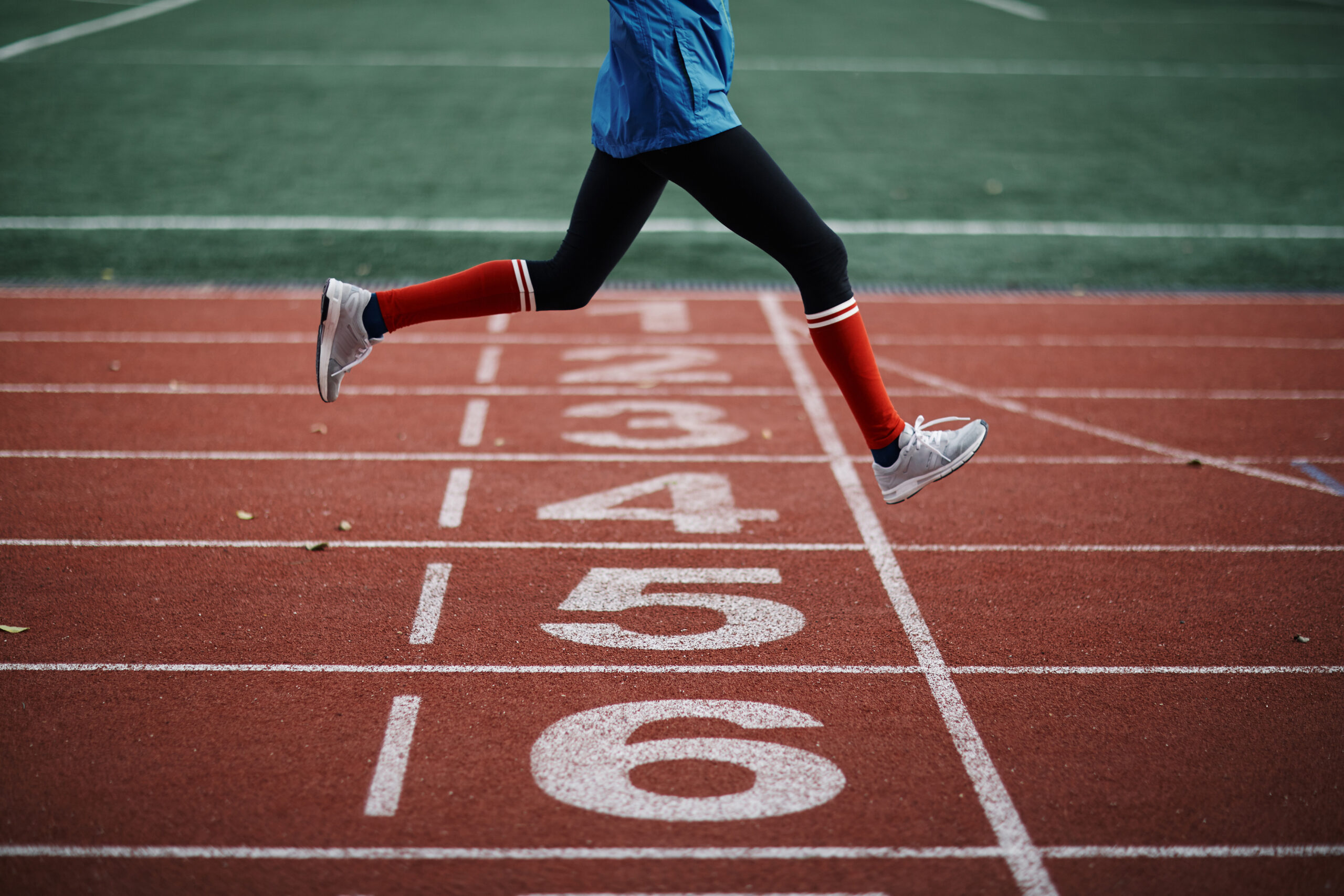 Male runner legs crossing the finish line on track