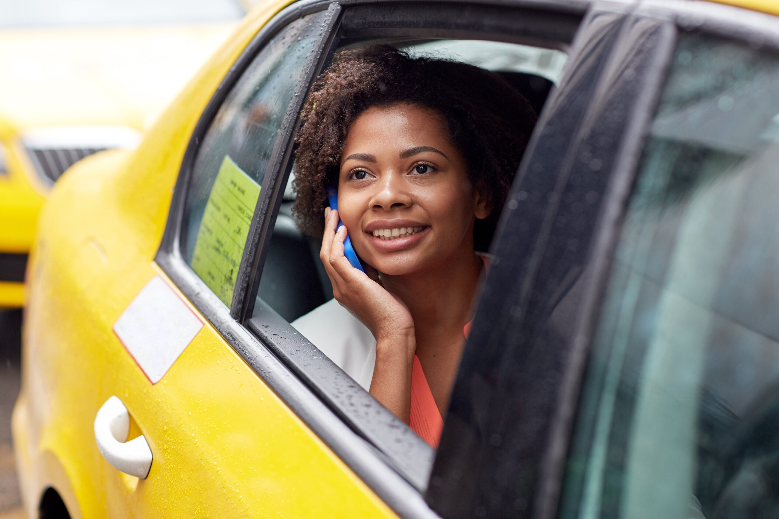 happy african woman calling on smartphone in taxi