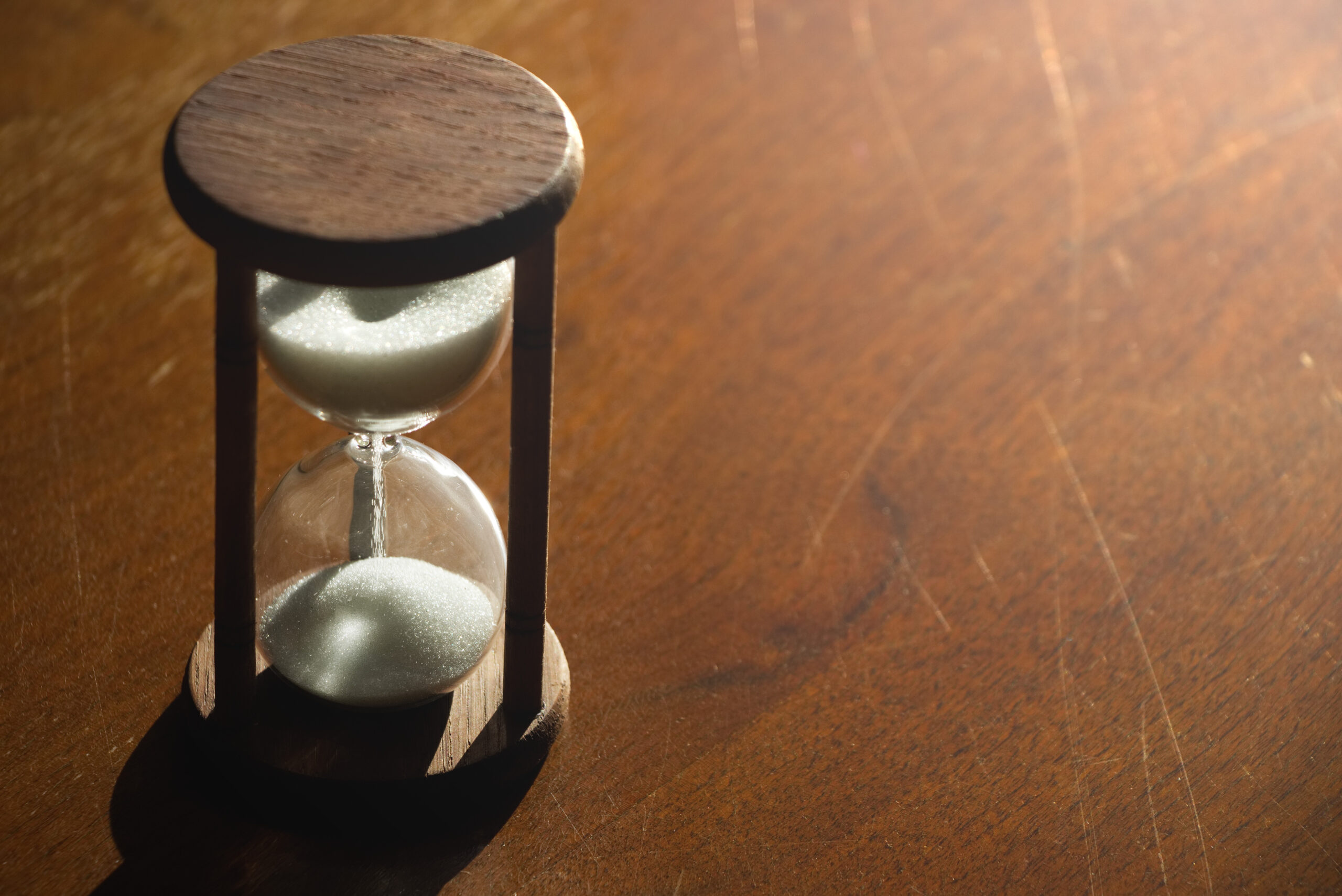 Hourglass time passing in contrast backlit. sandglass on a wooden background