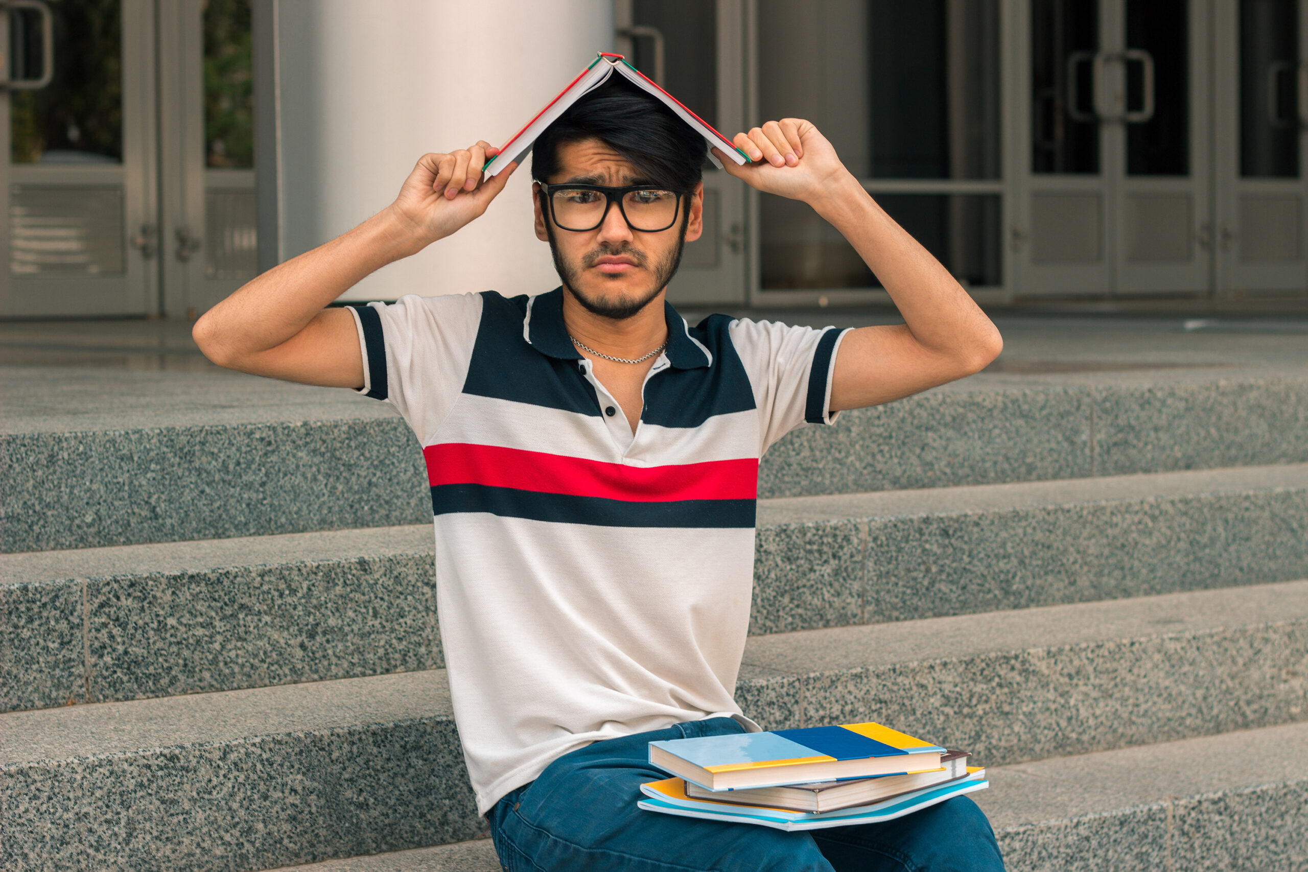 funny guy sitting on the street and keeps a book on your head