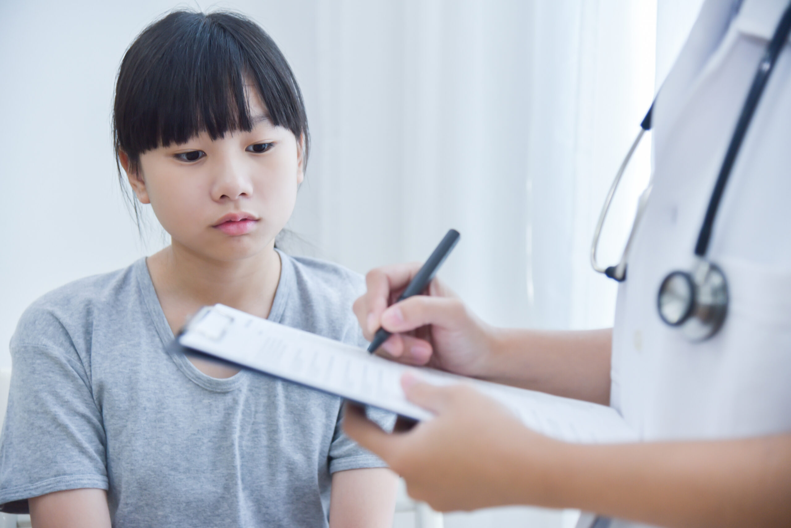 Doctor taking note on checklist for a little girl patients.