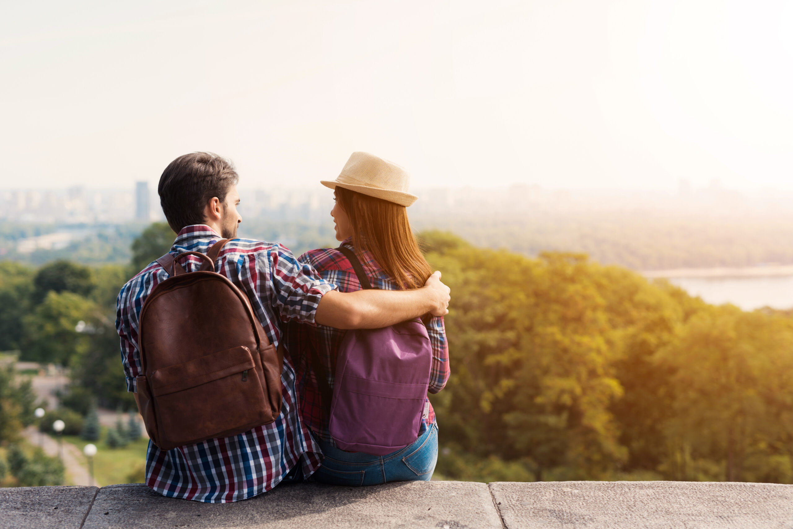 A young couple of tourists are sitting on the parapet. They look into the distance.