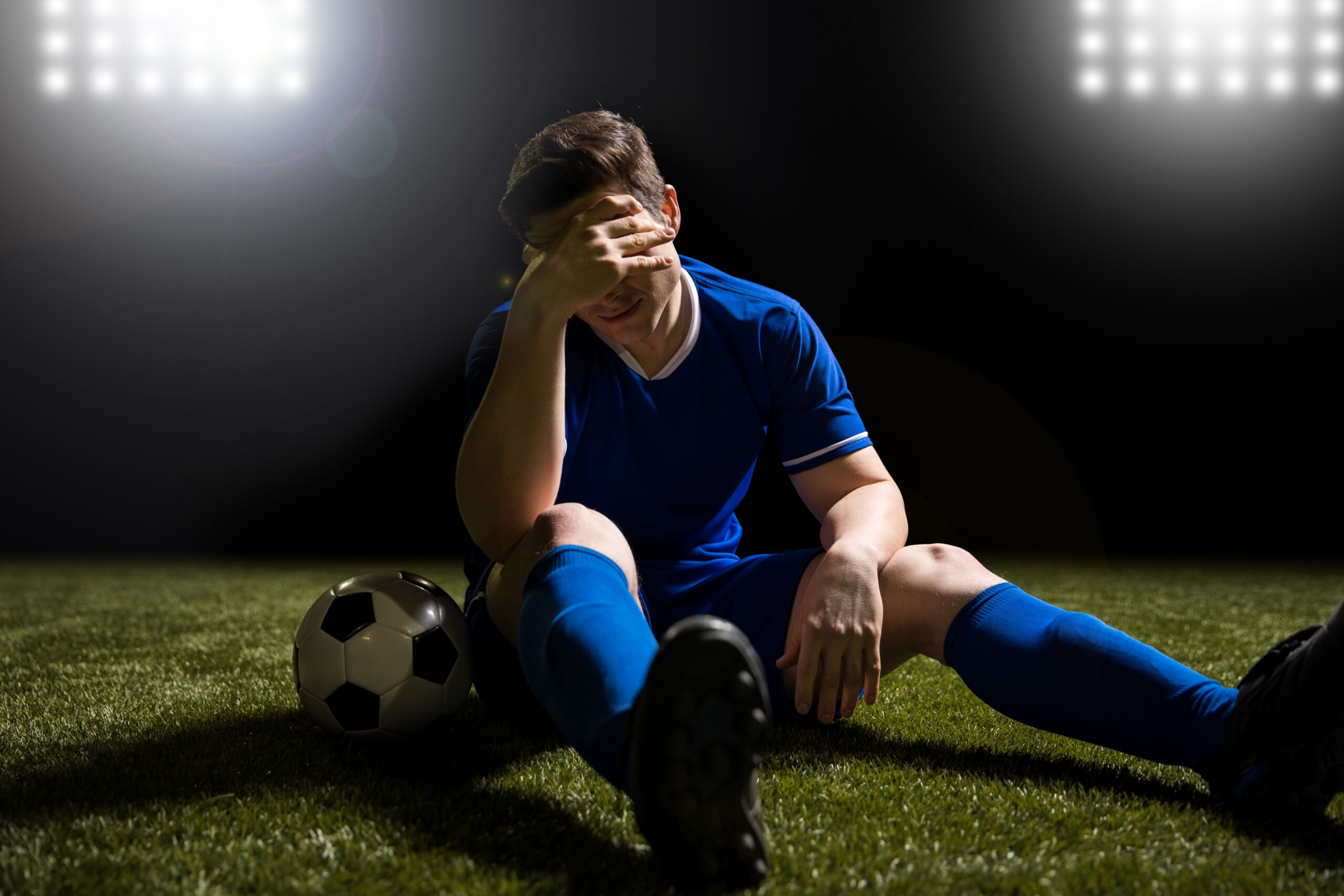 Disappointed soccer field sitting on dark field