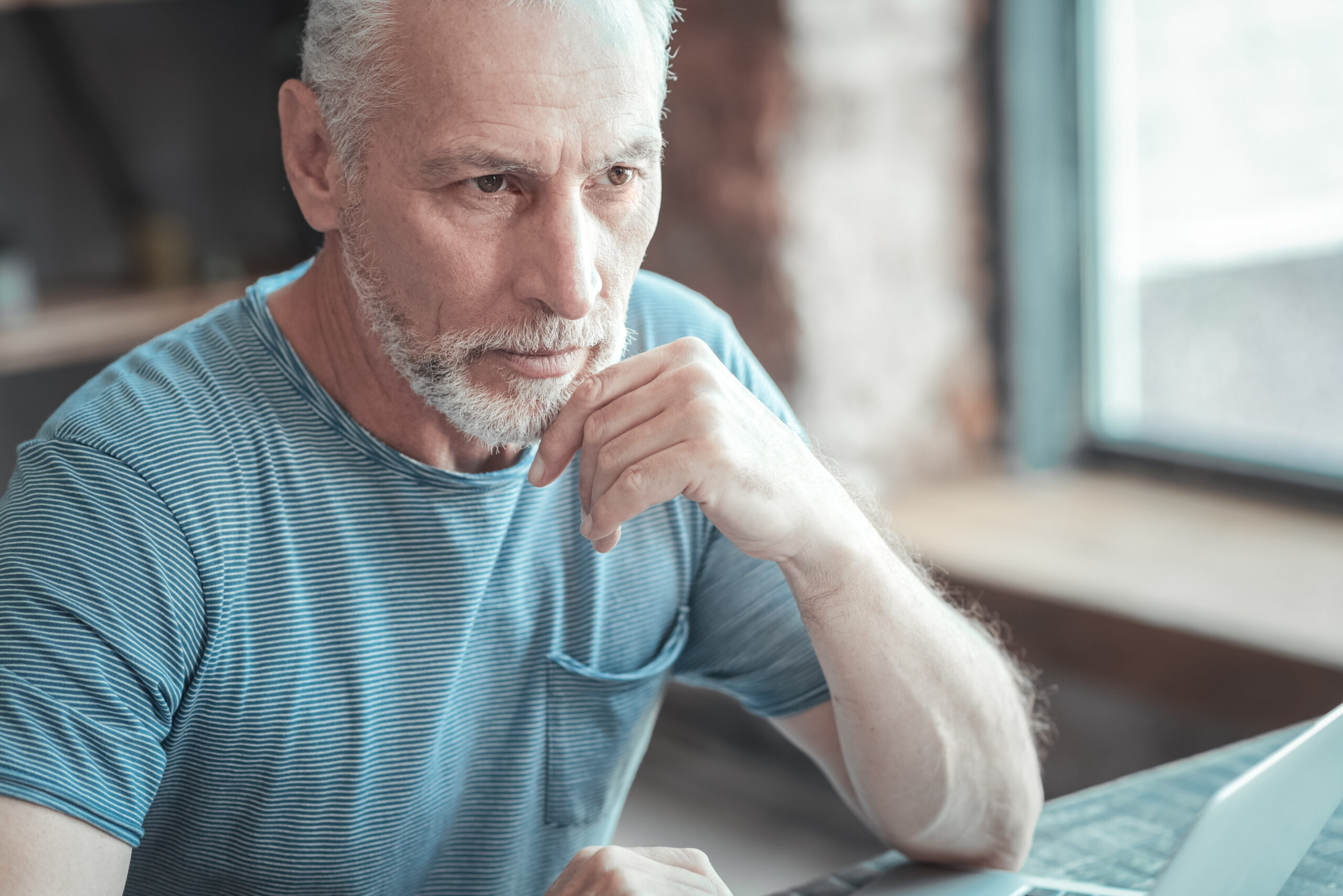 Thoughtful senior man looking at his computer