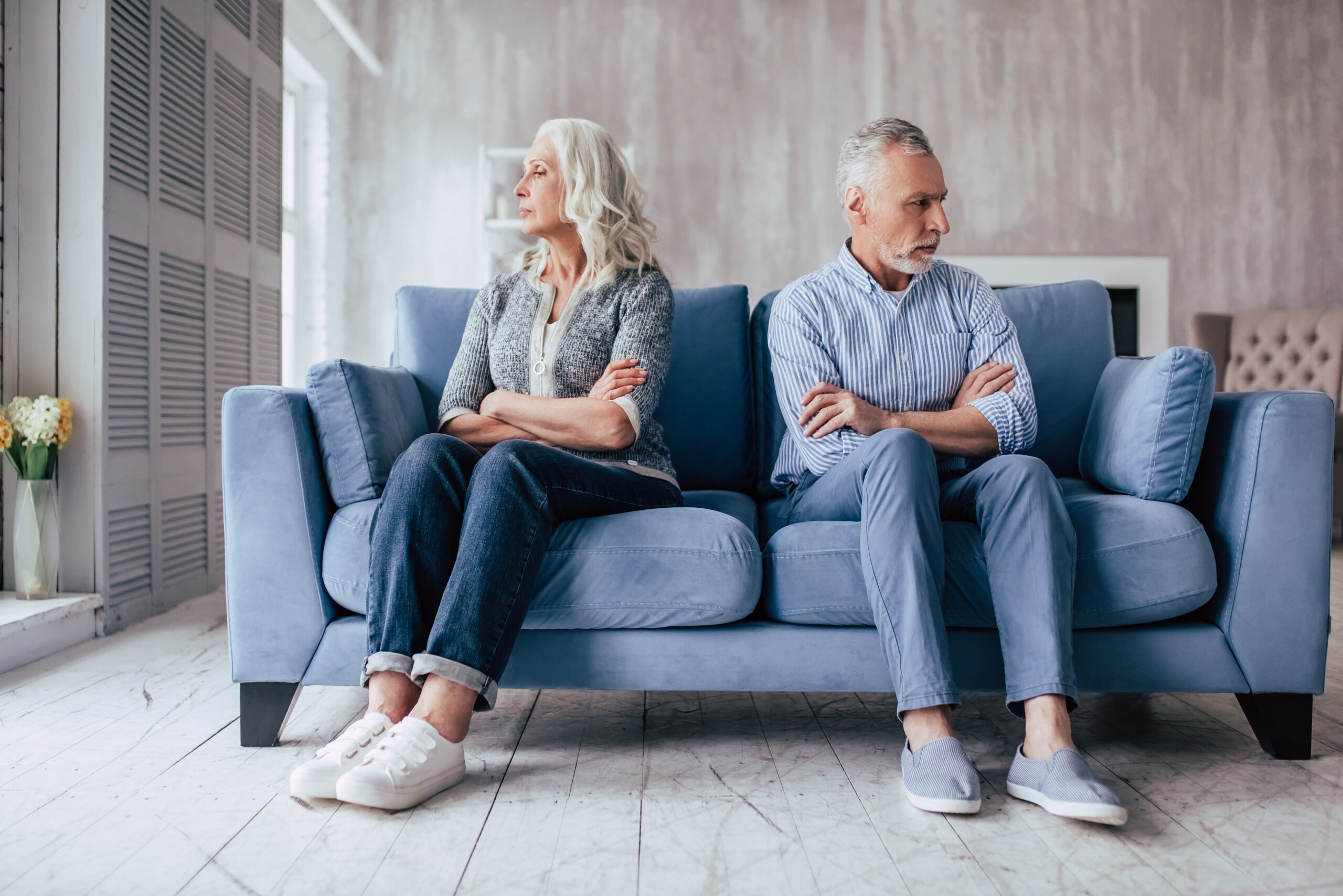 Angry senior couple sitting on opposite ends of couch