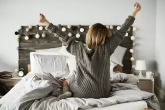 Rear view of woman stretching in her bed