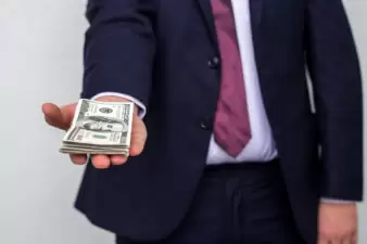 businessman holding out a stack of cash