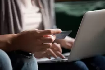 Woman holding credit card while using laptop