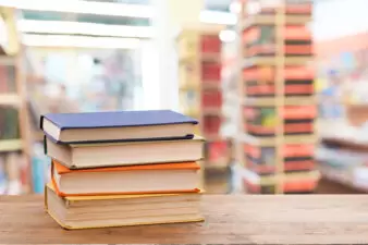 stack of hardcover books on a wood desk