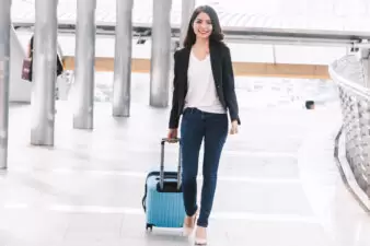 Happy businesswoman pulling a rolling suitcase at the airport