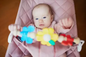 Baby girl playing with toys in bouncer