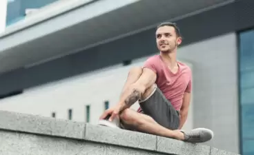 Tattooed man doing yoga asana on street