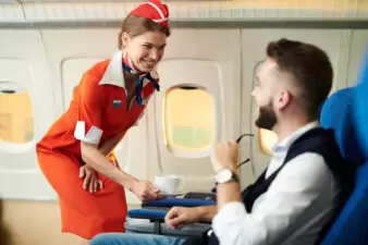 Flight attendant serving coffee to male passenger