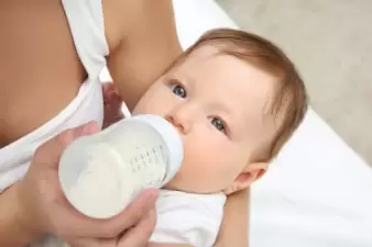 Mother holding and feeding baby from bottle