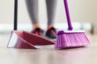 woman holding a purple broom and red dustpan