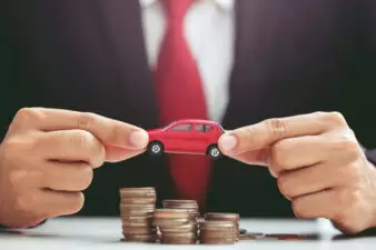 Man holding red car over coins