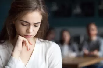 Sad young girl feeling lonely sitting alone in cafe