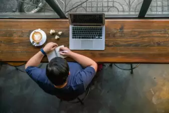 High angle view of man at his desk with laptop and cup of coffee