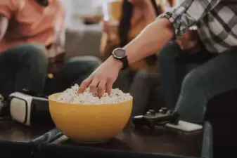 hand grabbing from a yellow bowl of popcorn