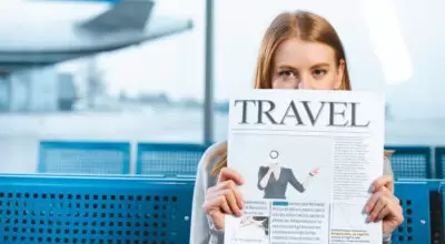 woman covering face with travel newspaper in waiting hall