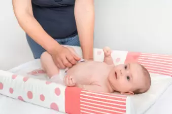 Mother changing baby on changing pad