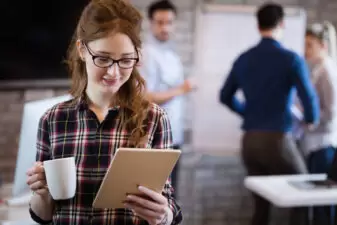 Young woman holding coffee looking at paperwork