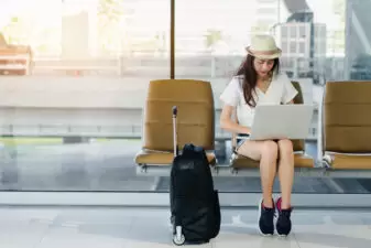 Woman sitting on her laptop with her luggage waiting on flight