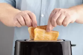 close up of a man taking bread out of a black toaster