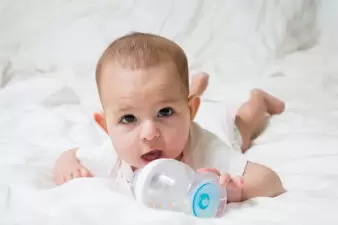 Baby on bed with bottle