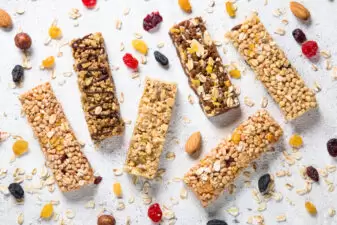 Granola bar with nuts, fruit and berries on white