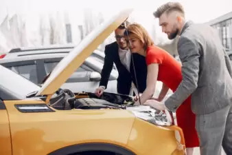 Man and woman looking at car engine with salesman