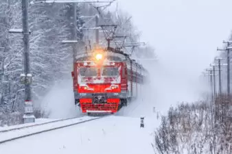 Red train traveling through snow