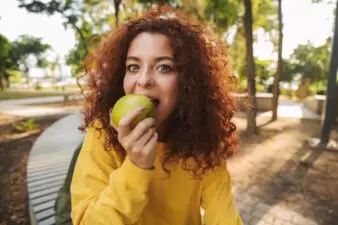 young woman eating a green apple