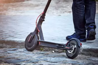 Man holding his scooter on the side of the curb